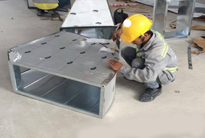 Kỹ thuật viên EVNCO đang thi công bông thủy tinh bọc bạc cách nhiệt cho đường ống gió.